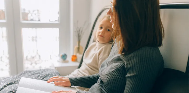 A mom reads to her daughter from a braille book